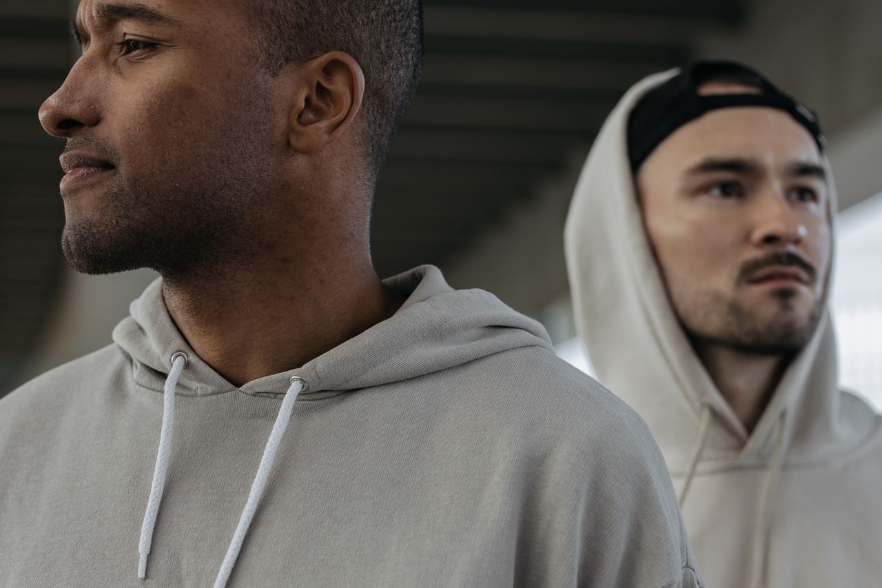 Close-up of two men in hoodies looking away in an urban setting. Selective focus.